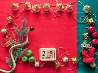 赤いフェルトの上に置いた色々なクリスマスオーナメントと12月25日を表示した木製のカレンダー