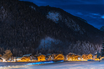 Snowy night winter view of an Italian mountain village. Malborghetto Valbruna, Julian Alps, Italy. Dreamy alpine landscape. Long exposure photography.