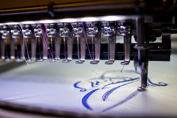 Embroidery with an industrial embroidery machine on textiles with blue thread. Mother and child...