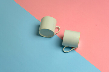 closeup studio photo of two mini coffee cups on pink blue background
