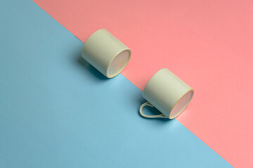 closeup studio photo of two mini coffee cups on pink blue background