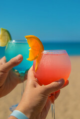 Woman on the beach holding a cocktail in her hands. Selective focus.