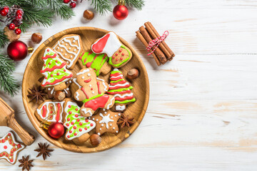 Christmas gingerbread in the plate with spices and decorations on white wooden table. Christmas baking. Top view with copy space.