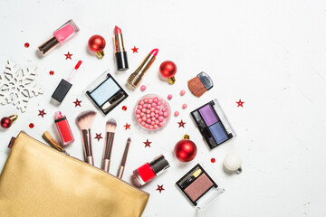Make up products with christmas decorations. Lipstick, powder, shadows with cosmetic bag. Flat lay image with copy space.