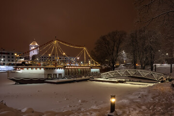 Colorful ship with festive lights frozen in river at Christmas time. Restaurant on water at winter....