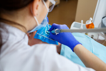 Fototapeta premium A dentist treats a male patient with dental instruments. The dentist examines the teeth of the patients in the dental clinic. Selective focus