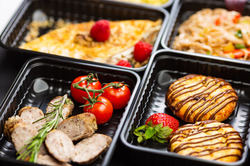 Ready healthy food catering menu in lunch boxes meat and vegetable packages on black table background