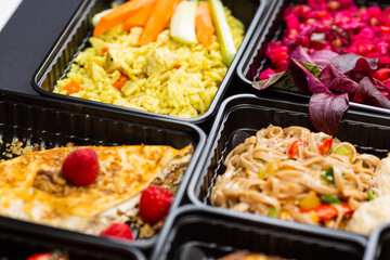 Ready healthy food catering menu in lunch boxes meat and vegetable packages on black table background