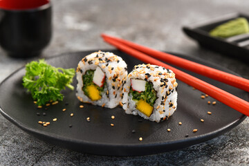 Uramaki Sushi couple on dark plate. Studio shoot on slate background.