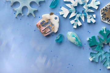 Handmade Christmas toys made of painted epoxy resin in the shape of a rural pink house, snowflakes...