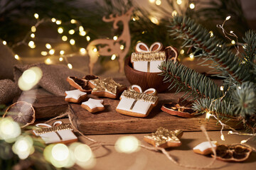 Christmas or New Year background with gingerbread gift box cookies, gingerbread stars, and fir tree branch on dark brown background. 