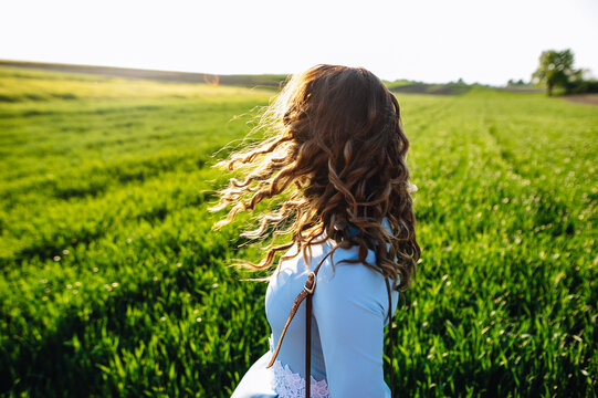 Young woman standing on street with hair blown by the wind, covering her face. Young casual girl with wavy hair. Dark-haired  woman with messy windy tousy blowsy hair, long wavy hair fly in the wind