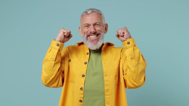 Happy charismatic surprised shocked vivid elderly gray-haired bearded man 50s wears yellow shirt look camera show mind explosion gesture isolated on plain pastel light blue background studio portrait