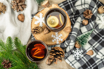 Hot black tea and lemon with winter decor. Cozy sweater, fir tree branches, nuts, snowflakes