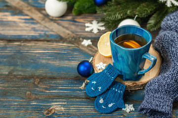 Hot drink with crocheted funny mittens. Traditional winter decor, fir tree branches, snowflakes