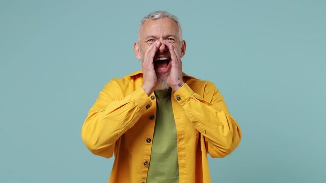 Promoter charismatic elderly gray-haired bearded man 50s wears yellow shirt scream hot news about sales discount with hands near mouth isolated on plain pastel light blue background studio portrait