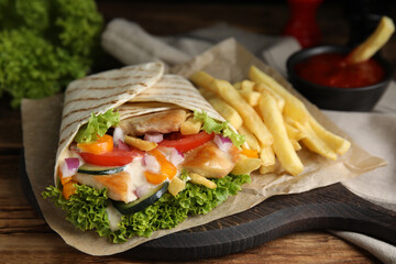 Delicious chicken shawarma and French fries on wooden table, closeup