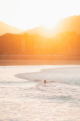Silhouette of a lonely surfer riding a wave during sunset in San Sebastian beach
