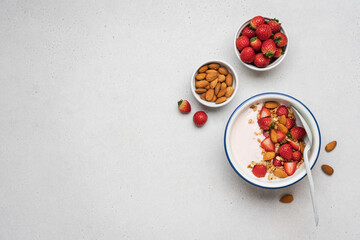 Strawberry yogurt with fresh berries, homemade granola, almonds in bowl. Healthy breakfast on light...