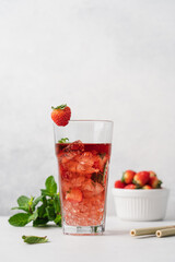Strawberry lemonade in transparent glass with ice. Refreshing summer berry lemonade with mint on white background