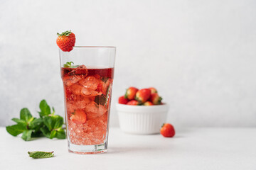 Strawberry lemonade in transparent glass with ice. Refreshing summer berry lemonade with mint on white background