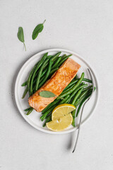 Grilled fried salmon fillet with green bean pods and lemon. Healthy sea food in plate on white background