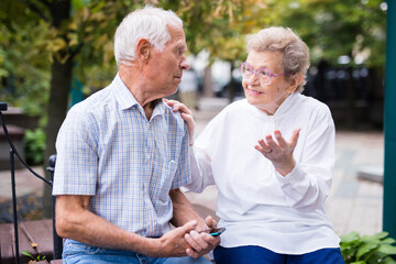 mature man with a woman sitting on bench in spring