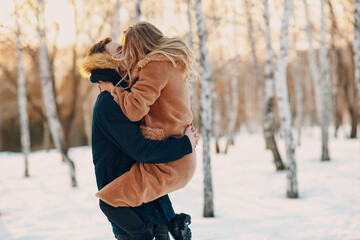 Loving young couple hugging kissing and having fun in winter forest park.