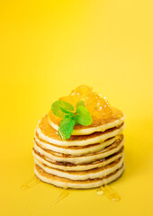 stack of freshly home made pancakes isolated over bright yellow background, traditional americal breakfast meal, studio photo shot. High quality photo
