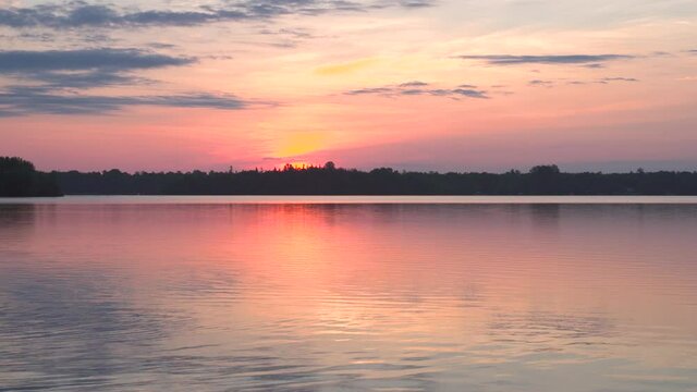 Sunrise over lake in northern Michigan; pink tones in sky and on clear, calm lake water--some early morning sounds of bird call. 633
