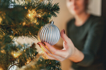 Girl decorates Christmas tree with bright glass balls, stars and a garland. © Evgenii Starkov