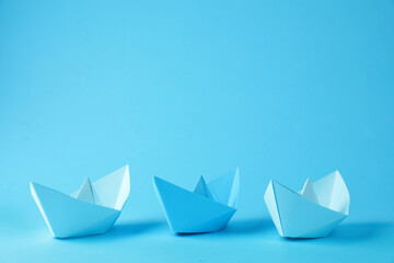 Handmade paper boats on light blue background.  Space for text