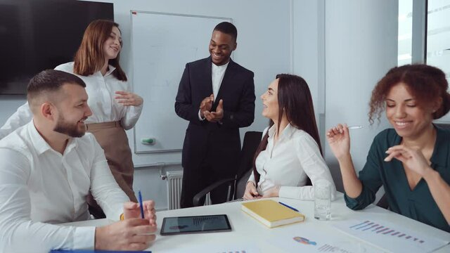 Group of multiethnic managers smiling at meeting in office. Tracking shot cheerful colleagues working together in friendly atmosphere. Concept of business