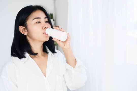 Asian woman drinking yogurt, fermented milk from bottle, healthy drink dairy product
