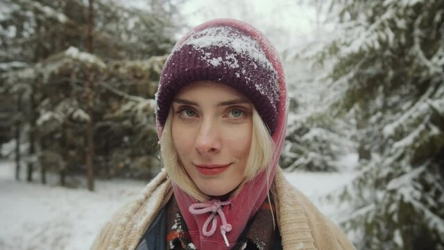 Portrait of young beautiful woman posing for camera in winter woods