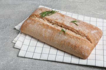 Fresh crispy ciabatta with rosemary on grey table