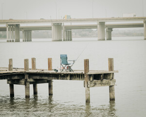 Folding camp chair with fishing tackles and standing rod on pier jetty at Lake Ray Hubbard, Texas,...