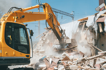 Excavator bucket breaks old house. Building demolishing for renovation.