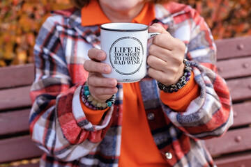 Elderly woman's hand holding white vintage cup of hot tea on a clear cold autumn day
