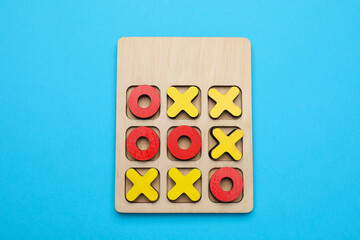 Tic tac toe set on light blue background, top view