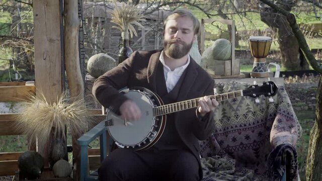 Man with a beard plays banjo merrily. Man with a beard plays the banjo fervently
