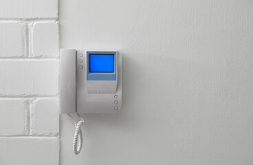 Modern intercom with camera installed on white wall