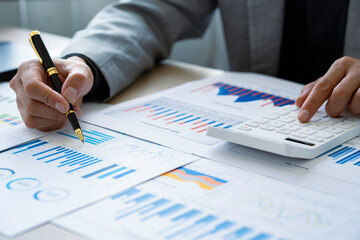 Close up of businessman or accountant hand holding pen using calculator to calculate numbers with...