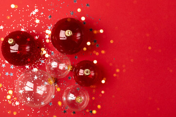Red and transparent christmas decoration balls on a red background with place for text. Holiday concept.