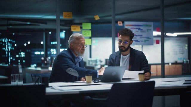 Businesspeople in Modern Office: Business Meeting of Two Managers. CEO and Operations Director Talk, Discuss, Brainstorm Corporate Strategy, Implementing Marketing and Financial Plans. Evening Time.