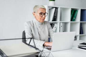 senior businesswoman in glasses working on laptop in office