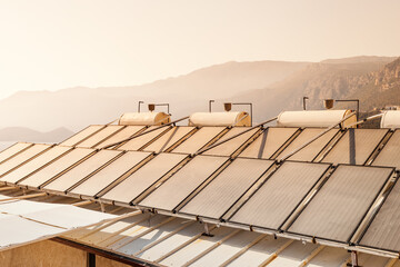 Solar panels and a water barrel are installed on the roof of the house as a source of hot water and heating. Green and eco-friendly renewable energy concept.