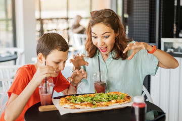 Mother and son eat delicious Italian pizza in a pizzeria or cafe. Joint leisure and fast food concept