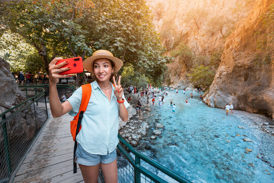 Woman travel blogger takes a selfie for social networks in a deep gorge of the Saklikent Canyon in Turkey. Cool blue water attracts many tourists