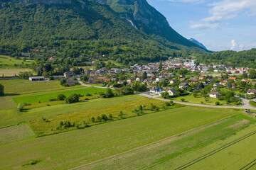 Fototapeta na wymiar The town of Gresy sur Isere at the foot of the mountain and wheat fields in Europe, France, Isere, the Alps in summer on a sunny day.